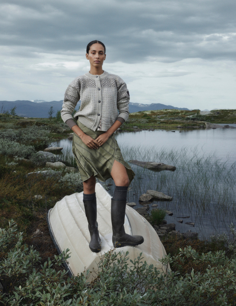 Hannah genser i Nature undyed ullkvalitet. Kvinnelig modell i norsk natur med mørke skyer i bakgrunn